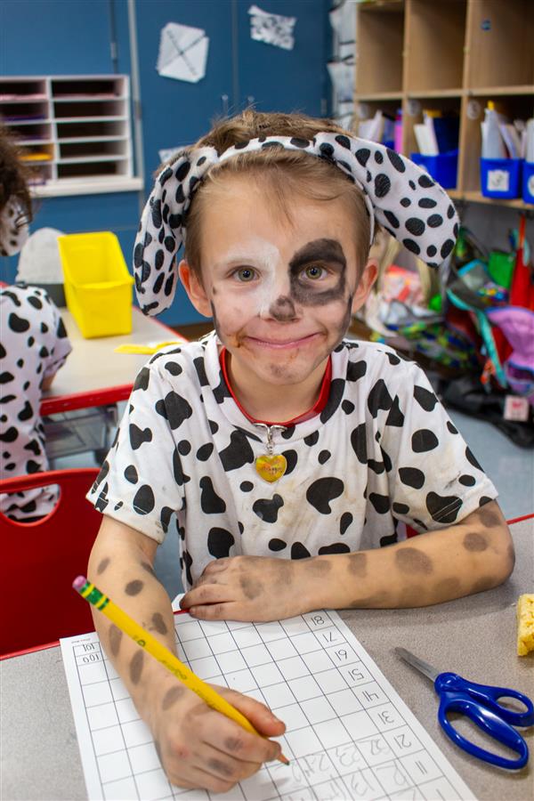 student dressed as dalmatian dog writing on paper